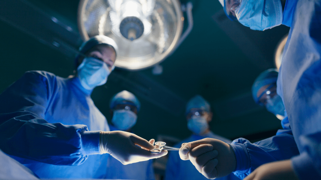 Surgeons and Physician Assistants in scrubs and masks work together in an operating room, demonstrating teamwork during a critical surgical operation.